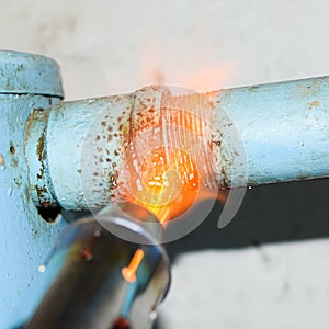 Heating a steel pipe with a blowtorch. The flame of