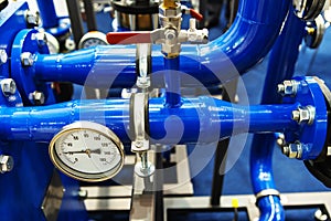 Heating system in an apartment building. Blue pipes with a pressure gauge in an industrial boiler room. Measuring equipment