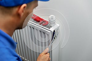 Heating system installation and maintenance service. plumber installing radiator