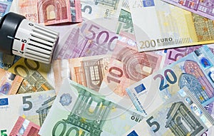 Heating thermostat with money, expensive heating costs concept