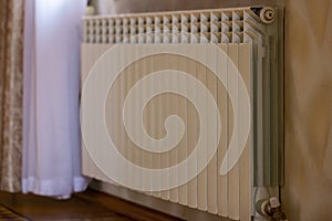 Heating white radiator radiator in living room with floor parquet