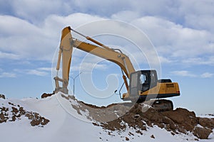 Heave yellow backhoe excavator, standing on the sand hill