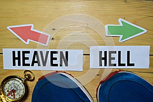 Heaven or Hell opposite direction signs with sneakers and compass on wooden