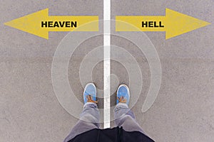 Heaven or Hell text on asphalt ground, feet and shoes on floor