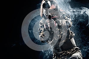 Heavily armed masked paintball soldier isolated on black background. Ad concept.