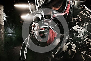 Heavily armed masked paintball soldier on post apocalyptic background. Ad concept.