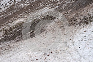 Heavily and extensively used fully worn out small sleighing hill in public park in winter with brown soil instead of snow