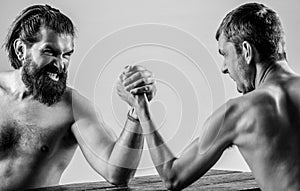 Heavily muscled bearded man arm wrestling a puny weak man. Two man& x27;s hands clasped arm wrestling, strong and weak