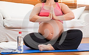 A heavily pregnant woman doing yoga.