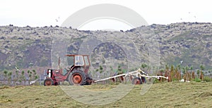 Heavily used red old tractor working on the field