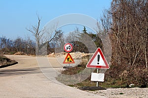 Heavily used warning and road under construction with 30 speed limit road signs next to paved road