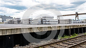 Heavy aluminum bars lying on each other on stack in the square of an aluminum smelter.