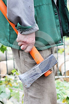 heavy ax with orange handle in his hand at the working men.