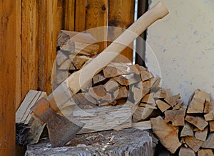 A heavy ax with rust, stuck in a log, a pile of chopped wood