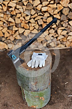 Heavy ax on the stump and protection gloves