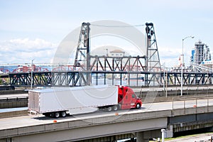 Heavy big rig bright red semi truck transporting semi trailer on