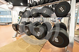 heavy black metal dumbbells for strength training on rack.