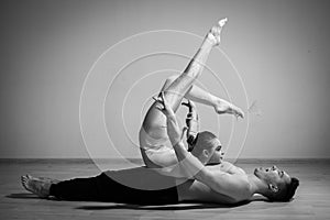 Heavy circus pose. A young man holds a flexible woman. Two acrobats or ballet dancers posing on a white background. A