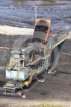 Heavy construction tipper trucks dump coal to the conveyor