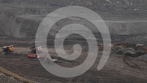 Heavy dump trucks ride along the open pit