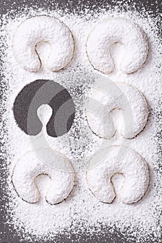 Heavy dusted vanilla crescents, with one missing, on a baking tray.