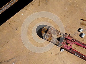 Heavy duty bolt cutter on top of old plywood formwork at the construction site.