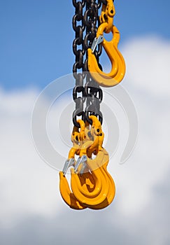 Heavy Duty Chain and Yellow Hooks against Cloud and Sky