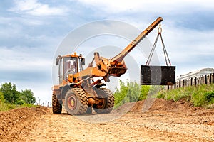 A heavy-duty construction vehicle or forklift driving along a dusty dirt road, stirring up clouds of dust as it moves forward