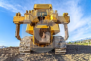 Heavy duty construction vehicle with peeling yellow paint and dirty metal tracks