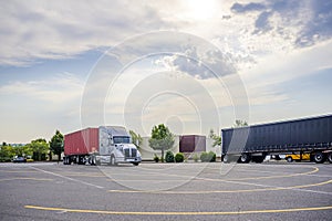 Heavy duty gray big rig semi truck with loaded container on the flat bed semi trailer standing on the parking lot for the rest at