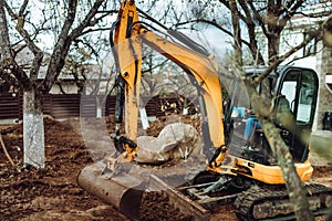 Heavy duty industrial excavator moving earth in the garden during landscaping works