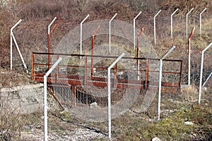 Heavy duty industrial old rusted metal bridge over water canal fenced off with protective wire fence