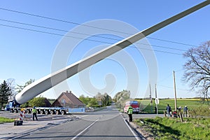 Heavy duty transport of a windmill blade lifted up to avoid obstacles such as a power lines on a narrow country road junction,