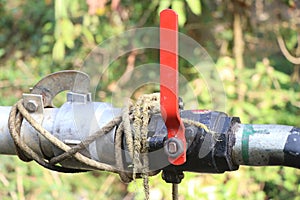 heavy duty water shutoff valve installed on a water carrying pipe. Ball valve threaded with red handle