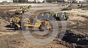 Heavy earthmoving equipment including scapers and motor graders involved in grading operations