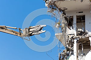 Heavy equipment hydraulic shears arrow dismantle the building, demolition destruction