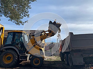 Heavy equipment near the destroyed brick house. Construction machinery on the background of the ruins of the house. Demolition of