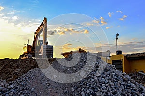 Heavy excavator bucket working in quarry on a background of sunset and blue sky