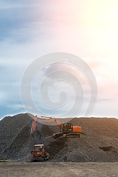 A heavy excavator and a bulldozer are working in a crushed stone factory