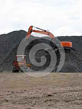 A heavy excavator and a bulldozer are working in a crushed stone factory