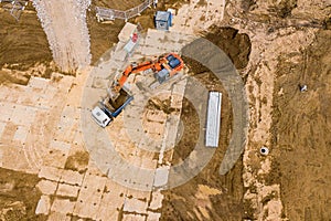 Heavy excavator and dump truck prepare ground for future construction works. aerial top view