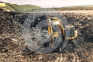 Heavy excavator loader, bulldozer working in garbage dump. Recycling and environmental issues