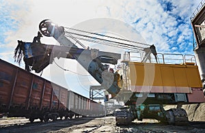 Heavy excavator loading gravel into train for rail freightage