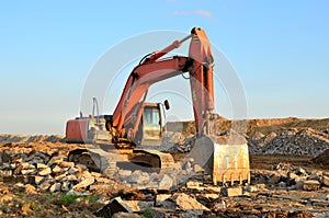 A heavy excavator in a working at granite quarry unloads old concrete stones for crushing