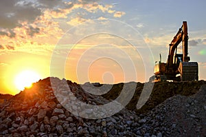 A heavy excavator in a working at granite quarry unloads old concrete stones for crushing and recycling to gravel or cement.