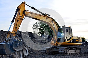 A heavy excavator in a working at granite quarry unloads old concrete stones for crushing and recycling to gravel or cement.