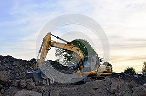 A heavy excavator in a working at granite quarry unloads old concrete stones for crushing and recycling to gravel or cement.