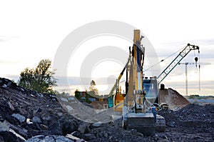 A heavy excavator in a working at granite quarry unloads old concrete stones for crushing and recycling to gravel or cement.