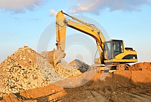 A heavy excavator in a working at granite quarry unloads old concrete stones for crushing and recycling to gravel or cement.