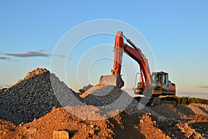 Heavy excavator in a working at granite quarry unloads old concrete stones for crushing and recycling to gravel or cement